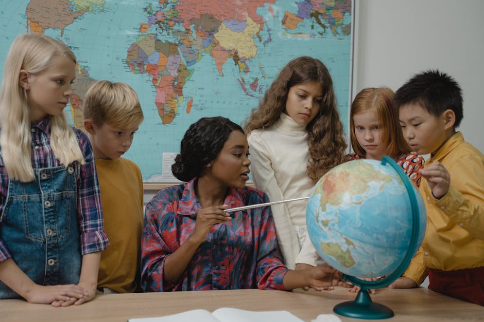 Diverse elementary students learning geography with a teacher and globe in the classroom